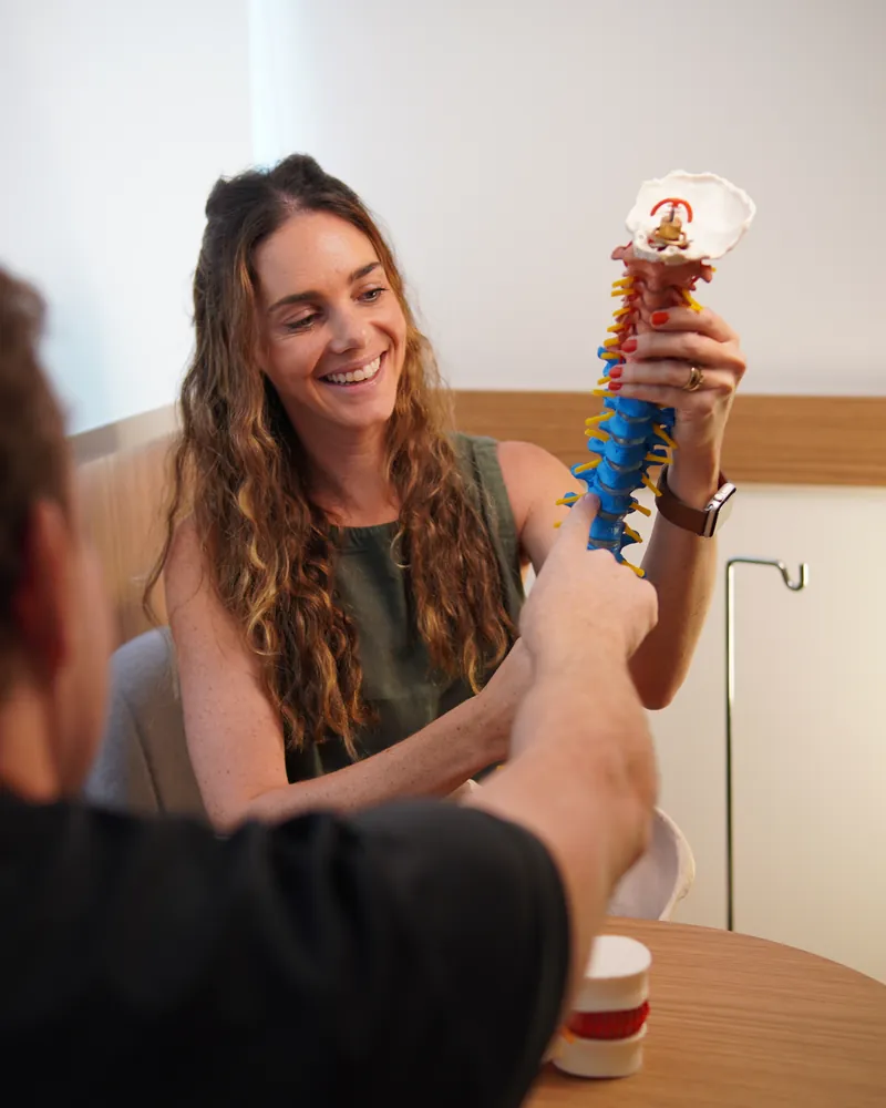 Janaína explica a um paciente a anatomia da coluna cervical em um modelo